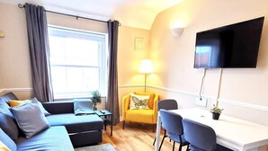 Ein modernes Wohnzimmer mit einer Couch, einem Sessel und einem Esstisch mit Stühlen.