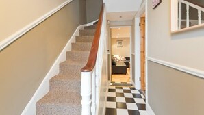 A staircase with carpeted steps and a wooden handrail, leading to a room with a checkered floor and a sofa. - Great House Trendy Ranelagh 3bed 2bath TV and WIFI (Dublin 6)