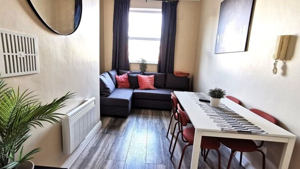 A compact living space with a sofa, a dining table, and a radiator. - Cosy Apartment near OConnell St Reliable Fast WIFI (Dublin 1)