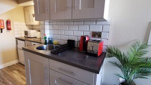 A compact kitchen with grey cabinets, a black countertop, a red toaster, and a sink. - Cosy Apartment near OConnell St Reliable Fast WIFI (Dublin 1)
