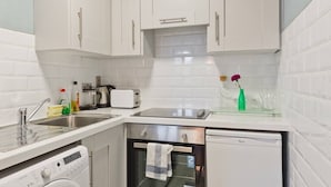 Eine moderne Küche mit weißen Schränken, einem Geschirrspüler, einem Backofen und einem Toaster.