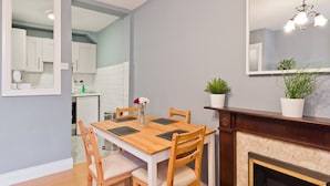 Ein Essbereich mit Holztisch und Stühlen, einem Spiegel über dem Tisch und einem Kamin mit zwei Blumentöpfen.
