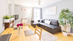 Ein modernes Wohnzimmer mit einem Holzesstisch, einem grauen Sofa und einem großen Fenster.