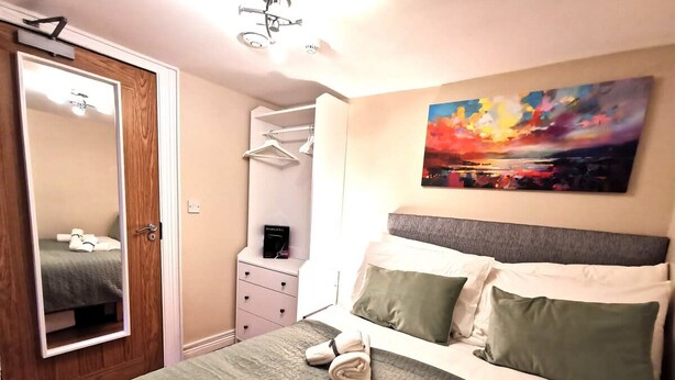 A bedroom with a bed, a wardrobe, a dresser, and a painting on the wall. - Good location Cosy flat Ranelagh (Dublin 6)