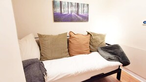 A bedroom with a bed, pillows, a blanket, and a wall-mounted painting of a forest. - Good location Cosy flat Ranelagh (Dublin 6)