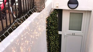 A white door with the number 11, a small window with a grid pattern, and a white wall with a white wire fence and string lights. - Good location Cosy flat Ranelagh (Dublin 6)