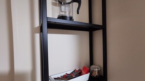 A black shelf with a glass coffee maker, a white box with red and black items, and a small jar. - Good location Cosy flat Ranelagh (Dublin 6)