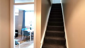 A staircase leading to an upper floor, a dining area with a table and chairs, and a door at the top of the stairs. - Central Apartment Private patio reliable fast WIFI (Dublin 1)