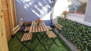A small enclosed patio with a table and chairs, a blue wall, and a green artificial turf floor. - Central Apartment Private patio reliable fast WIFI (Dublin 1)