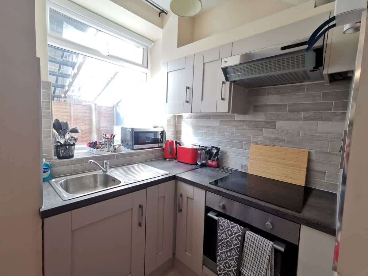 Eine kleine Küche mit Spüle, Mikrowelle, Toaster und einem Fenster für natürliches Licht.