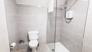 A modern bathroom with a glass-enclosed shower, a toilet, and a small potted plant. - Great new 2bed apartment in city centre*fast WIFI (Dublin 1)