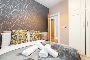 A modern hotel room with a large bed, decorative pillows, a marble headboard, and a view of the hallway. - Refurbished 2 BED APT WITH GARDEN Fast WIFI & TV (Stoneybatter)