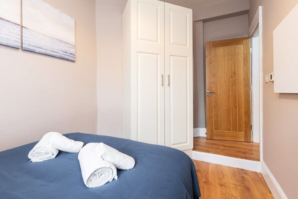 A bedroom with a bed, white wardrobe, and a wooden door. - Refurbished 2 BED APT WITH GARDEN Fast WIFI & TV (Stoneybatter)