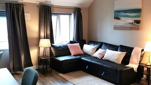 Un salon moderne avec un canapé en cuir noir, une petite table et une lampe.