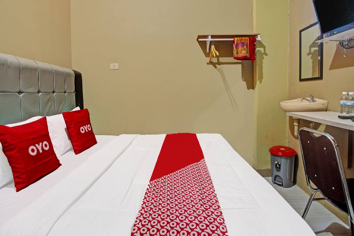 Une chambre d’hôtel équipée d’un lit, d’un bureau, d’une chaise, d’un lavabo et d’une poubelle.