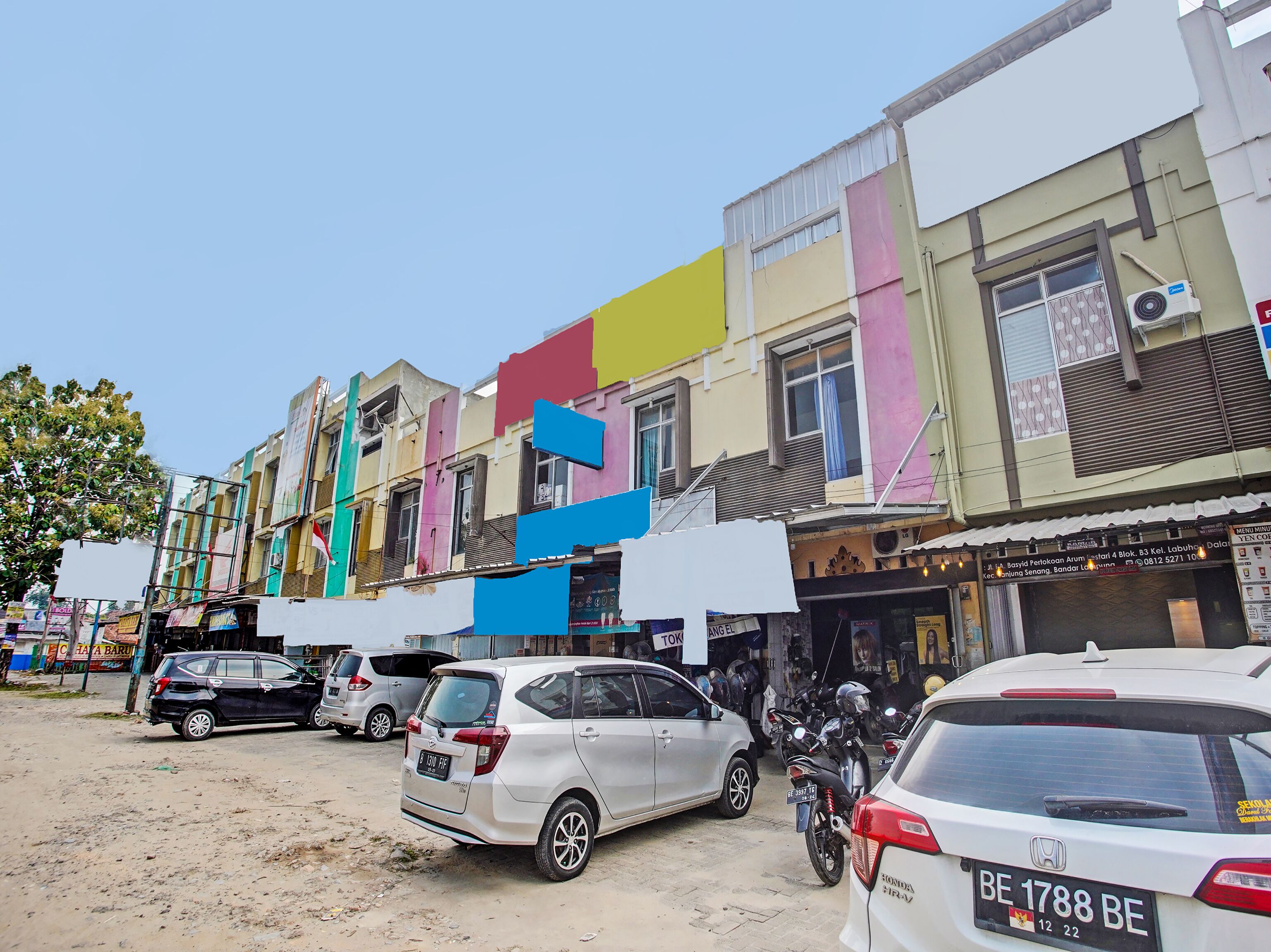 A street with colorful buildings, parked cars, and motorcycles.
