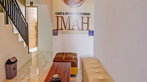 Een hotel lobby met een houten receptiebalie, een bank en een bord dat het lobbygebied aangeeft.