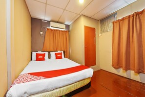 Une chambre d’hôtel avec un lit, un plancher en bois, une porte et un appareil de climatisation.