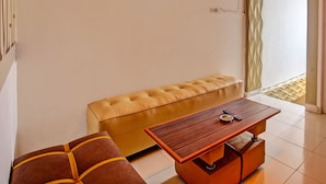 Een moderne woonkamer met een leren bank, een houten salontafel en een bankje.