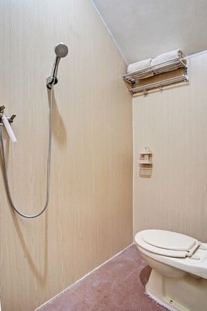 Une petite salle de bain avec une douche, des toilettes et un porte-serviettes.