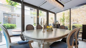 Un comedor con una mesa redonda, seis sillas y una lámpara de araña.