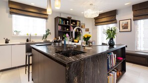 Una cocina moderna con una isla central, estanterías empotradas y un amplio ventanal con cortinas.