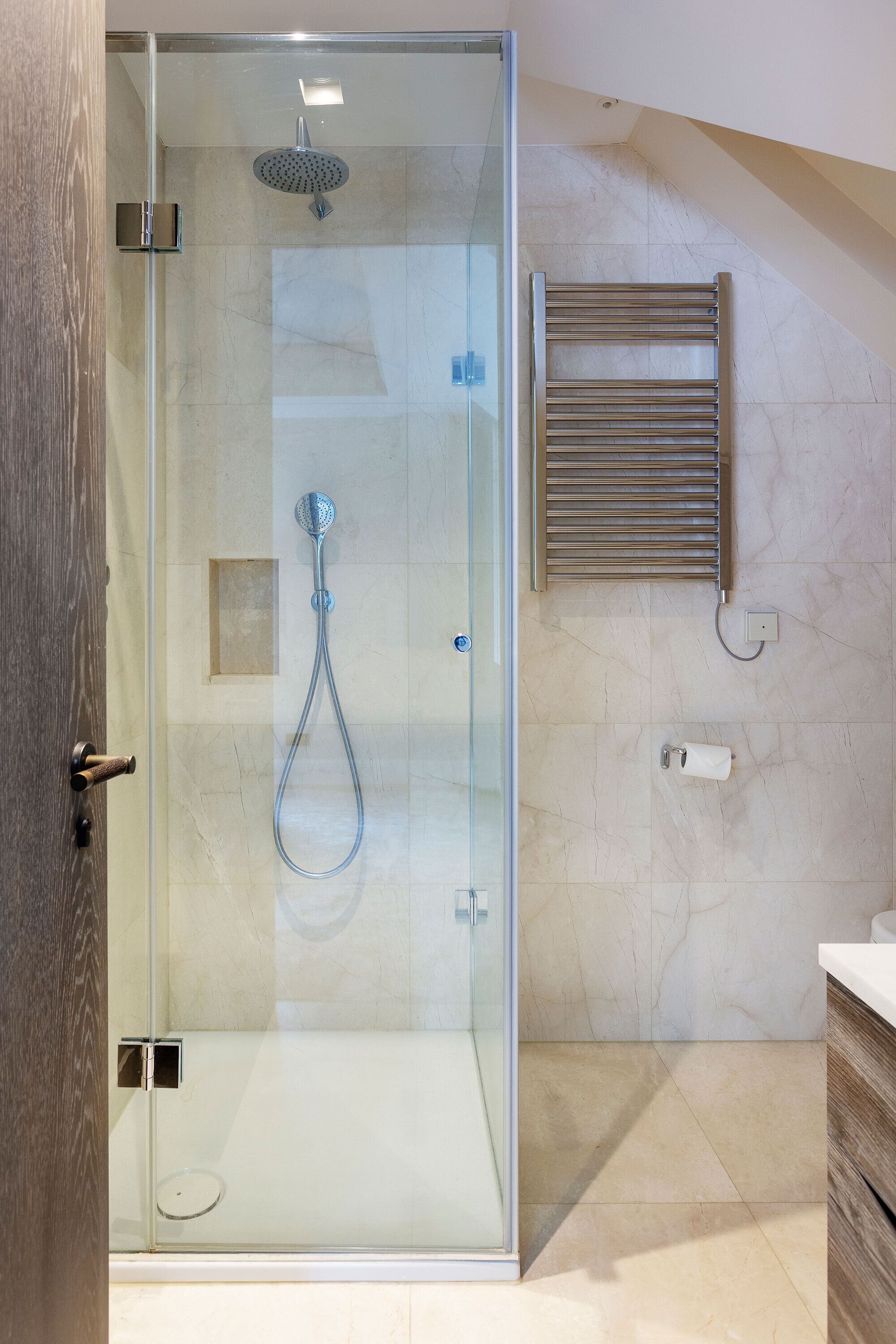 Une salle de bain moderne avec une douche en verre, un porte-serviettes et un sol carrelé en marbre.