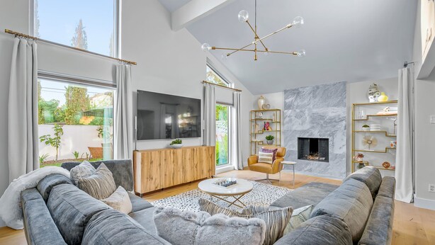 A modern living room with a large gray sofa, a wooden entertainment unit, and a fireplace.