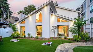 A modern house with a sloped roof, large windows, and a well-maintained lawn.