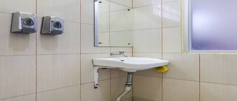 A bathroom with a sink, mirror, and two hand dryers.