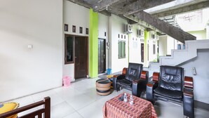 A spacious indoor area with a high ceiling, a staircase, and a seating area with chairs and a table. - OYO 3830 Dfarys Gh Syariah (Balikpapan)