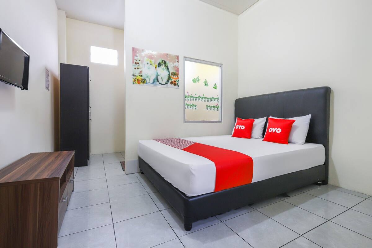 A neatly arranged hotel room with a bed, a TV, a wardrobe, and artwork on the walls.