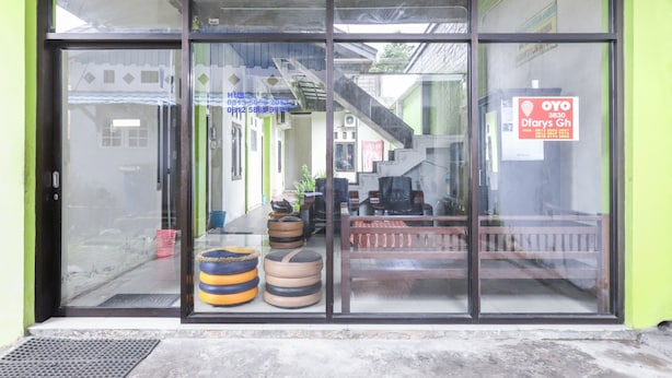 A hotel entrance with a glass door, a signboard, and a staircase leading to the upper floor. - OYO 3830 Dfarys Gh Syariah (Balikpapan)