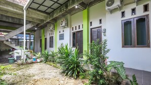 A building with multiple air conditioning units, a staircase, and a variety of potted plants. - OYO 3830 Dfarys Gh Syariah (Balikpapan)