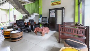 A hotel lobby with a staircase, seating area, and a reception desk. - OYO 3830 Dfarys Gh Syariah (Balikpapan)