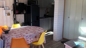 A compact kitchen with modern appliances, a dining area with a table and chairs, and a wooden floor. - Logement 6 Pers sur les Pistes de Skis vue Panoramique (Orcieres)