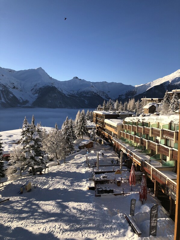 A snow-covered mountain resort with a ski lift, cabins, and a view of the lake.