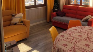 A cozy living room with a sofa, a red couch, and a dining table. - Logement 6 Pers sur les Pistes de Skis vue Panoramique (Orcieres)