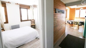 A bedroom with a bed, a chair, a window, and a wooden wall. - Logement 6 Pers sur les Pistes de Skis vue Panoramique (Orcieres)