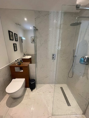 Ein modernes Badezimmer mit einer Duschkabine aus Glas, einem weißen Waschbecken und einem Holzlagerfläche.