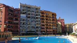 En swimmingpool omgivet af høje bygninger med altaner.