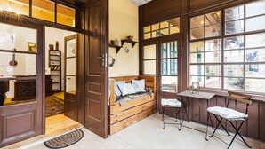 A cozy room with a wooden bench, a small table, and a window with a view. - Soví dom flat 1 (Svätý Anton)