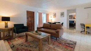 A living room with a sofa, a coffee table, a chair, and a television.