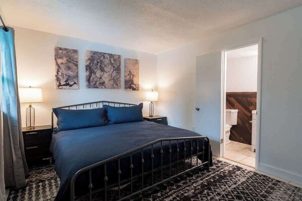 A bedroom with a metal bed frame, a patterned rug, and artwork on the wall.