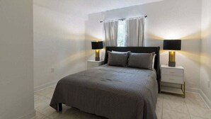 A bedroom with a bed, two bedside tables, and a window with curtains.