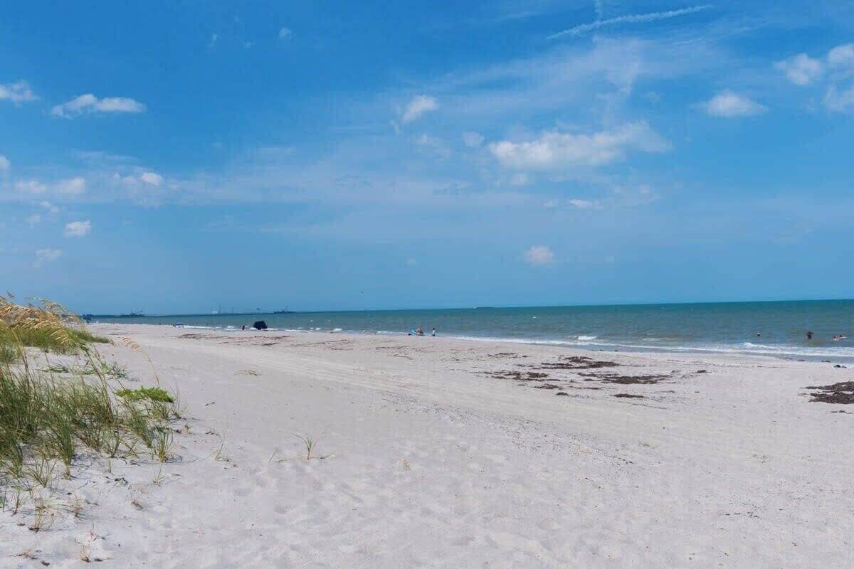 A beach with sand, sea, and a clear sky.