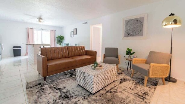 Ein stilvolles Wohnzimmer mit einem braunen Ledersofa, einem grauen Sessel und einem Couchtisch mit Muster.