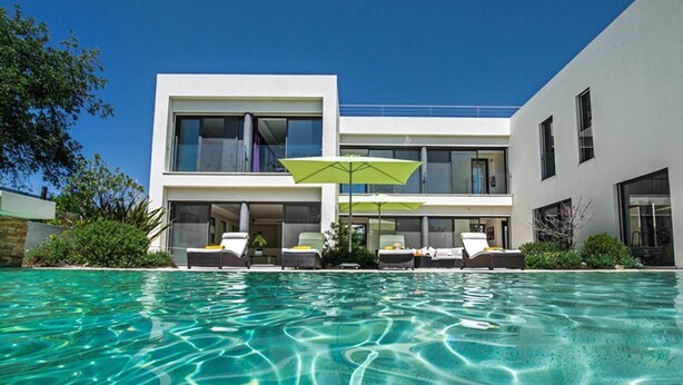 Et moderne hus med to etager og en swimmingpool foran.