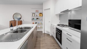 Une cuisine moderne avec des meubles blancs, un évier en acier inoxydable et une cuisinière à gaz.