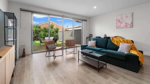 Un salon moderne avec un canapé vert, une table basse et un coin repas comprenant des chaises et une table.